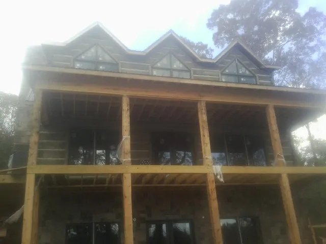 Dormers and porch framing on a large log home under construction — Roof Coating work by our crew in Kingston